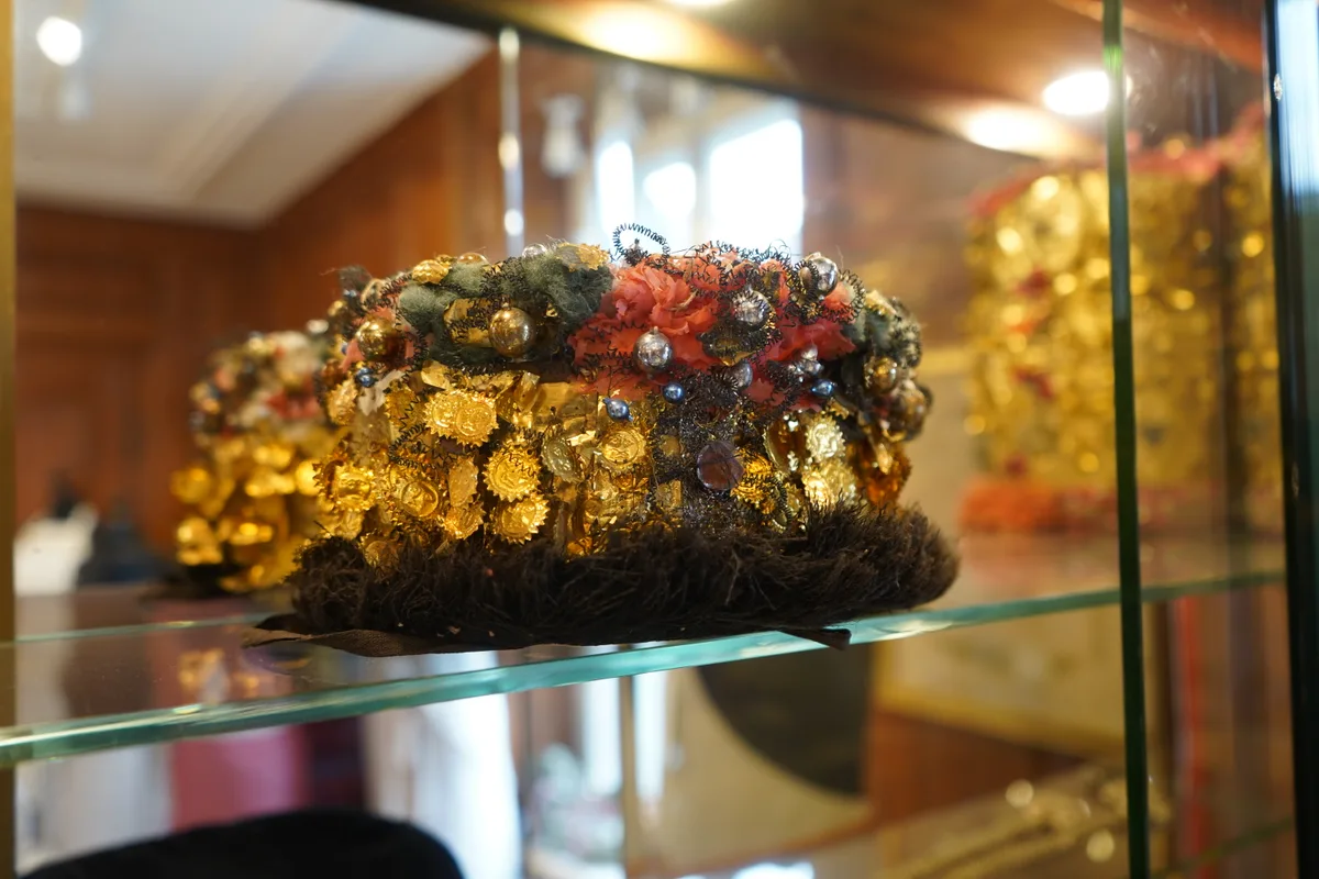 Eine Haube mit goldenen Blättern dran und einer blmenartigen Verzierung.